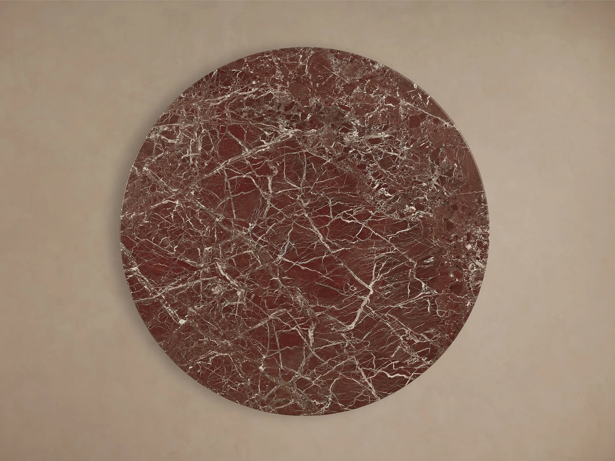 Front view of Saint Germain Round Stone Dining Table with Launette Base. Reddish-brown marble top with white veins, dark steel trumpet base.