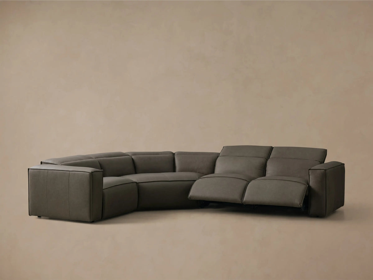 Front view of the charcoal leather Coburn Motion Leather Four-Piece Corner Wedge Sectional, with black piping.