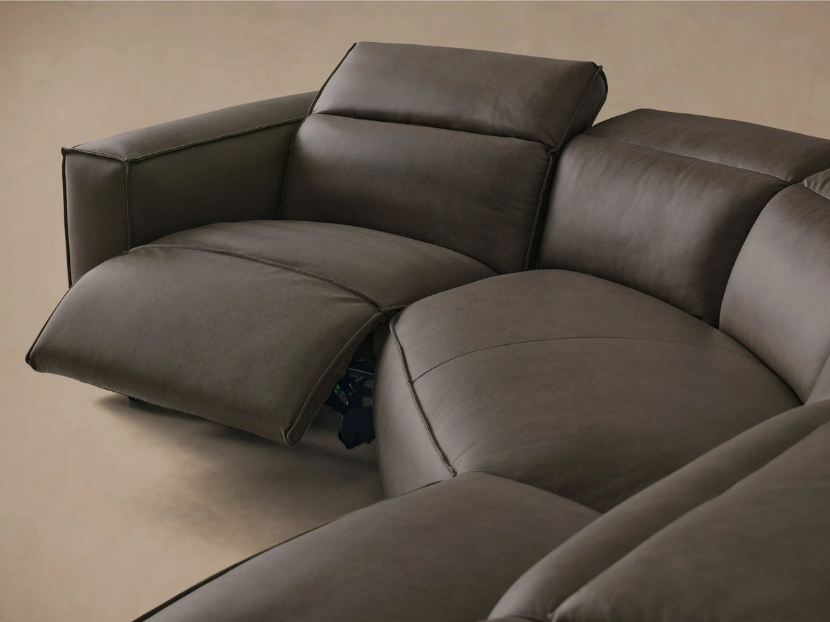 Front view of the dark gray Coburn Motion Leather Four-Piece Corner Wedge Sectional with one recliner extended.
