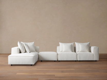 Off-white Coburn Five Piece Bumper Sectional, L-shaped, with chaise, ottoman, and 3 armless seats, on wood floor.
