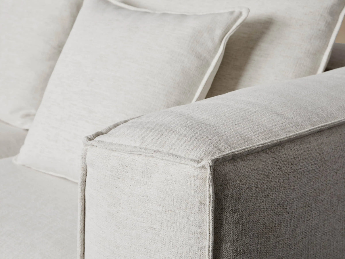 A large, L-shaped white Coburn Five Piece Bumper Sectional sofa with plush back cushions, resting on a warm wood floor.