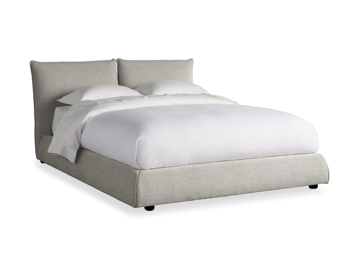 The Rigby Bed in Nomad with light gray upholstered frame, plush headboard, white bedding, and two pillows.
