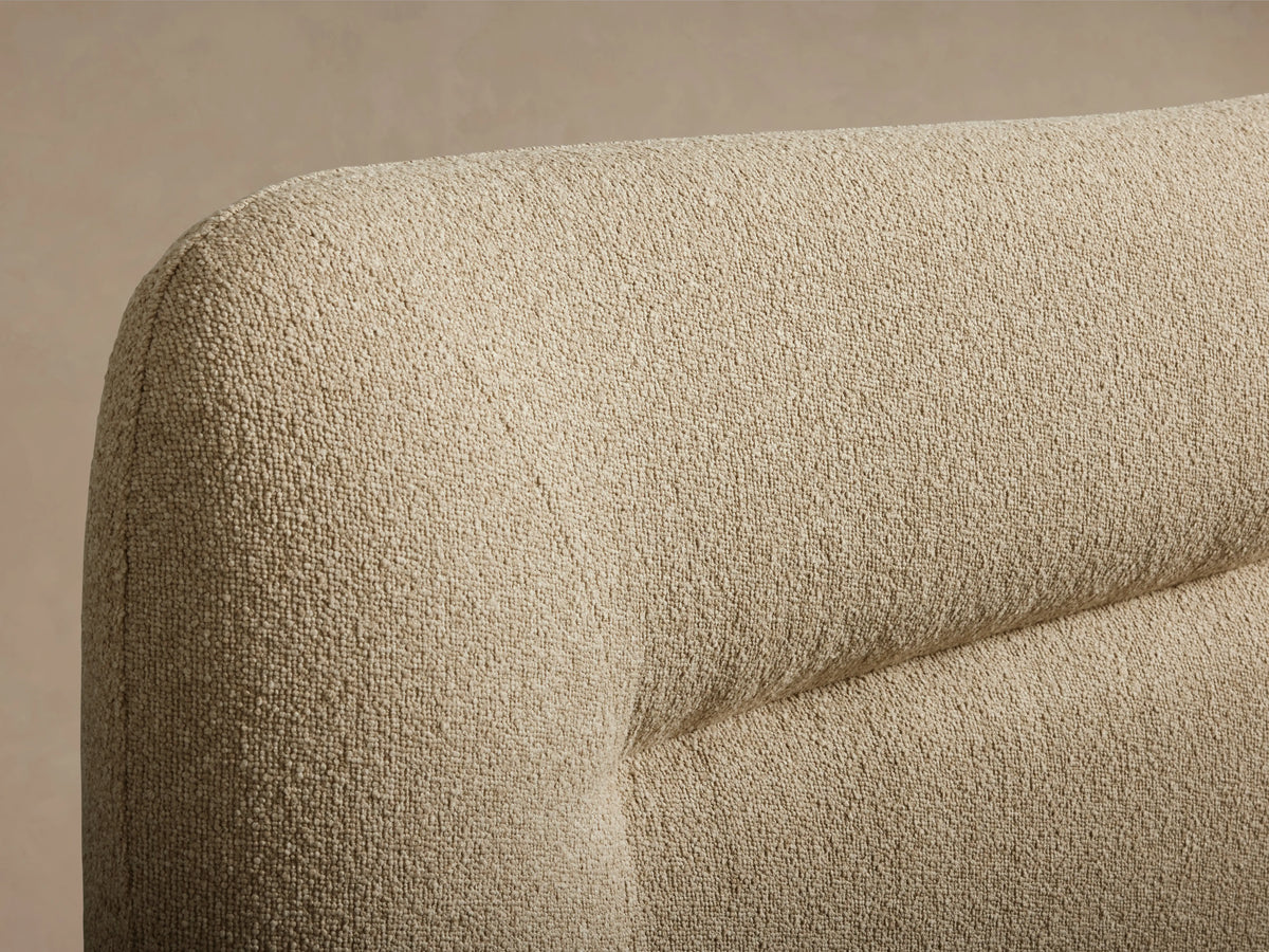 Close-up of the Lille Bed's curved headboard, showing the fawn-colored, textured performance fabric.