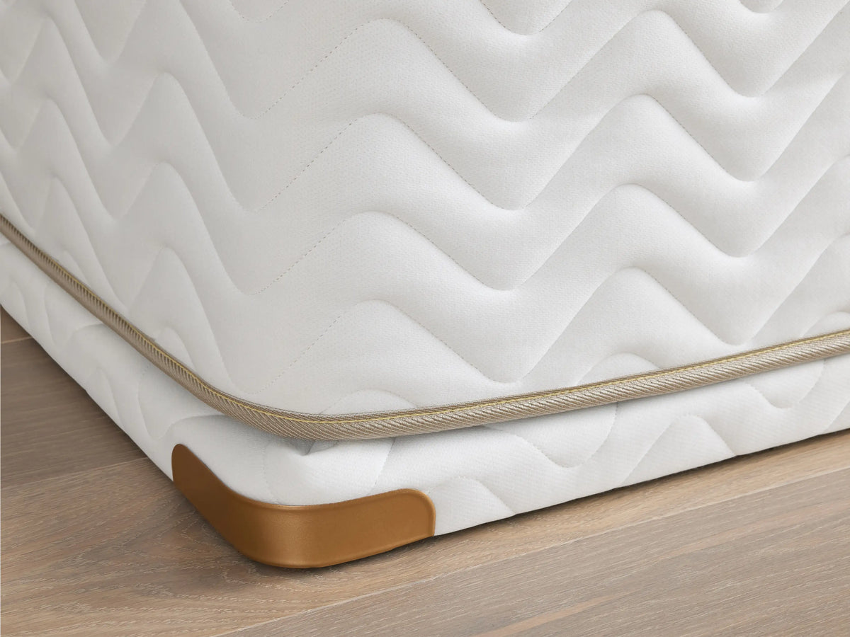 Premium 2" Platform corner with white fabric, wavy pattern, and brass-finished metal guard on a wood floor.