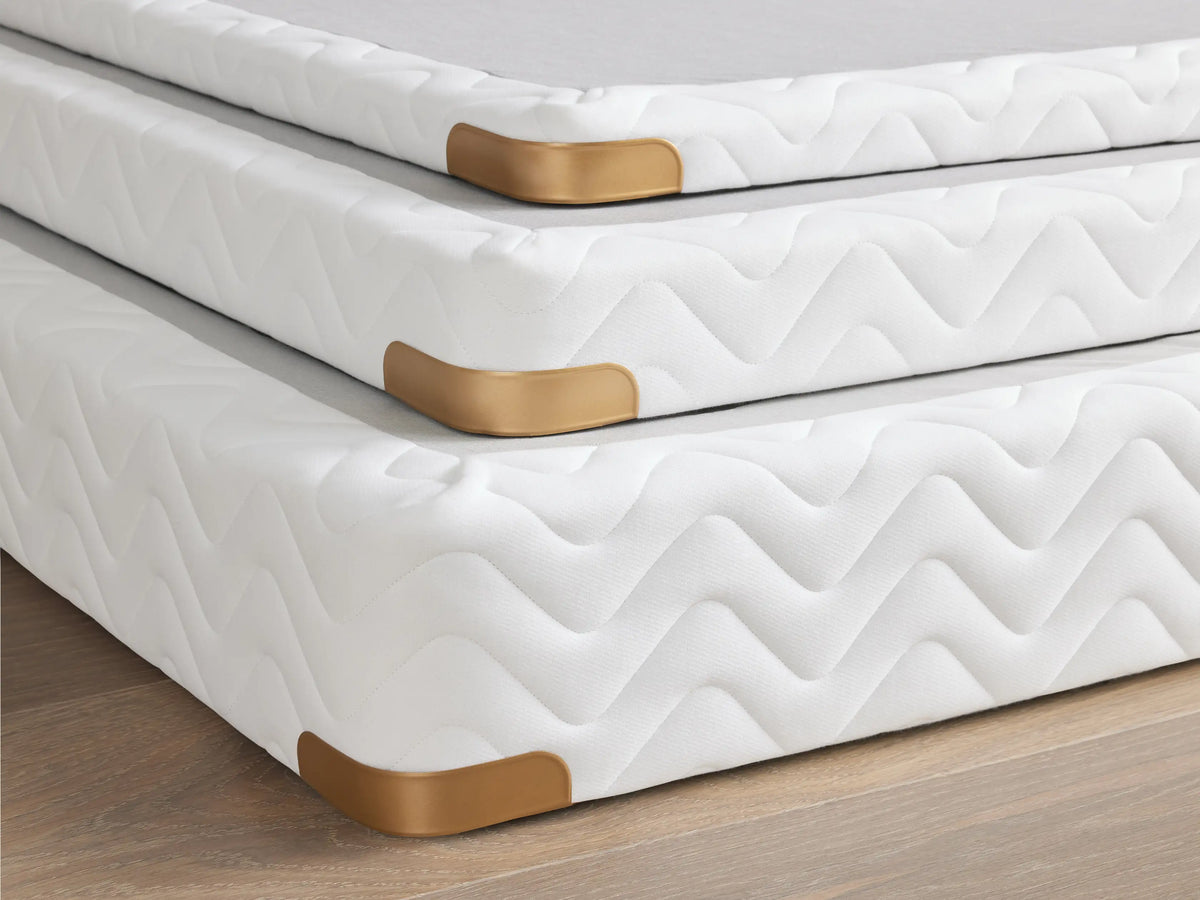 Premium 2" Platform with brass-finished corner guard, white fabric with a zigzag pattern, on a wooden floor.