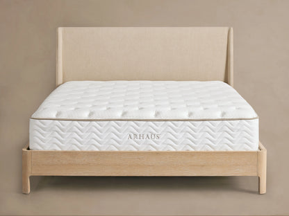 Premium Plush Mattress on a wooden bed frame with a beige headboard. The mattress is quilted white with a subtle geometric pattern.
