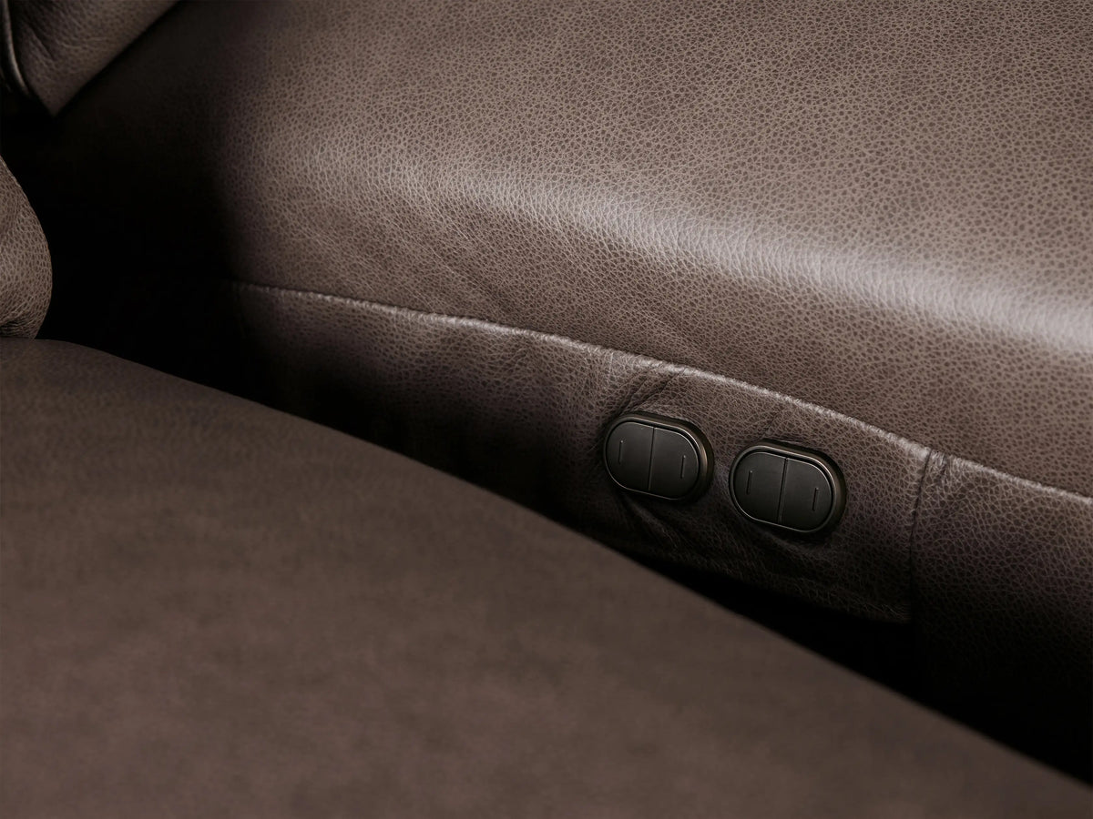 Close-up of a Brennan Leather Four-Piece Motion Sectional, highlighting rich dark brown leather texture and stitching on cushions.