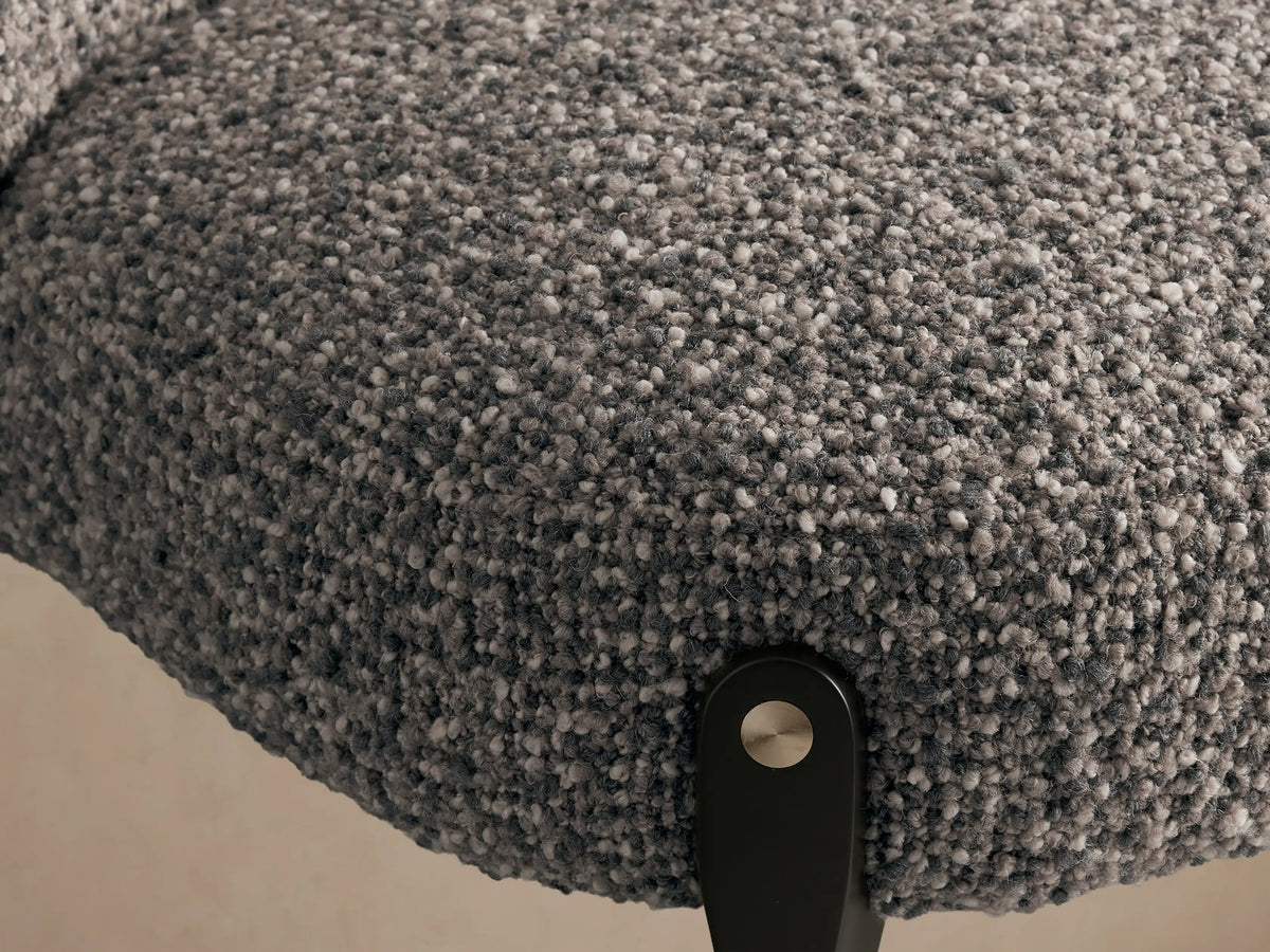 Bottoni Dining Chair: Front view of an upholstered dark grey textured chair with a rounded back, on dark angled legs with brass accents.