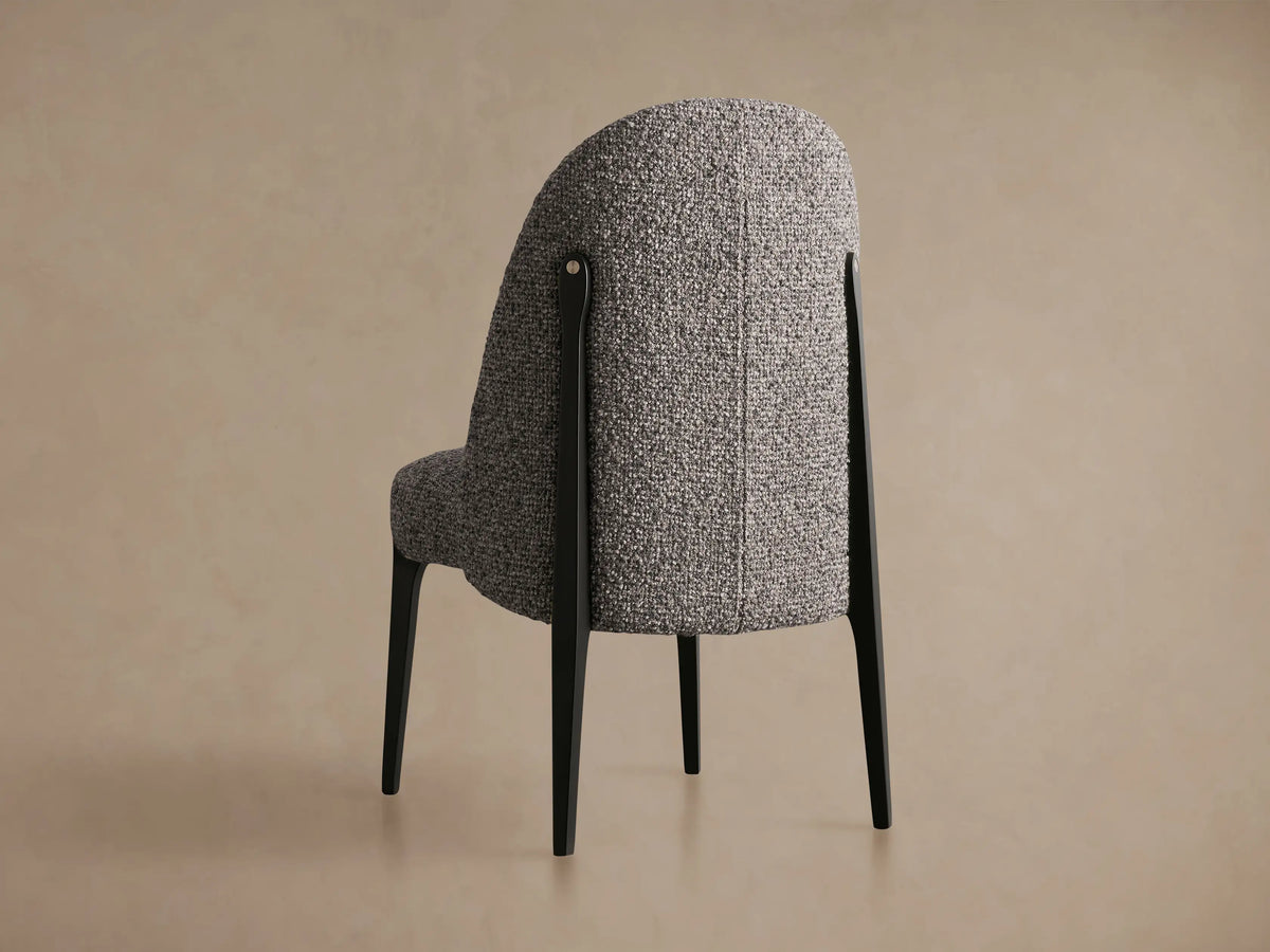 Bottoni Dining Chair's grey speckled boucle upholstery, with a black metal frame and silver rivet.