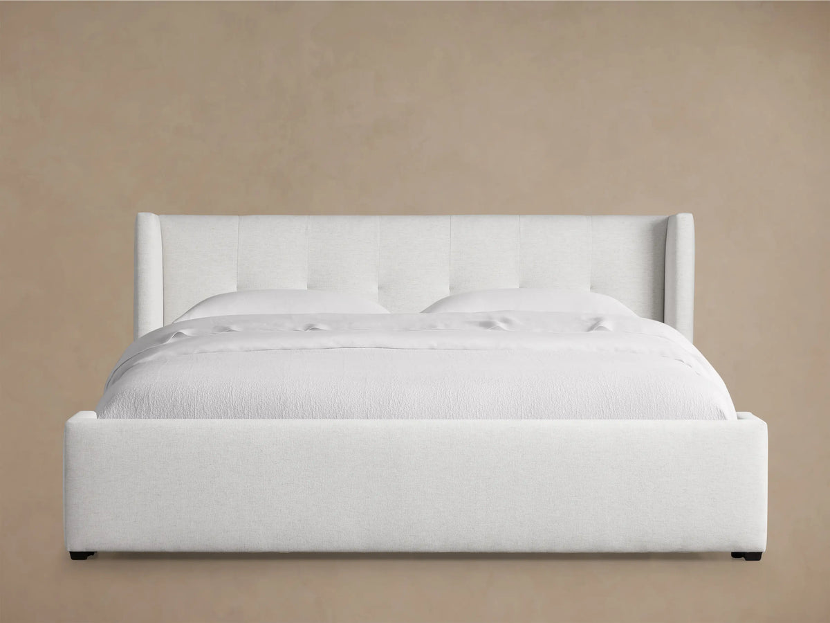 White Wyller Box-Tufted Bed with low footboard, upholstered in light fabric, featuring a box-tufted headboard. Angled view.