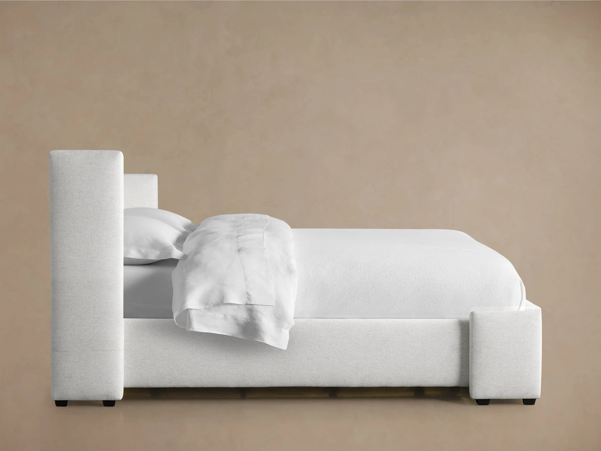 Close-up of Wyller Box-Tufted Bed's light gray woven fabric headboard, showing square tufting and a sturdy upholstered side panel.