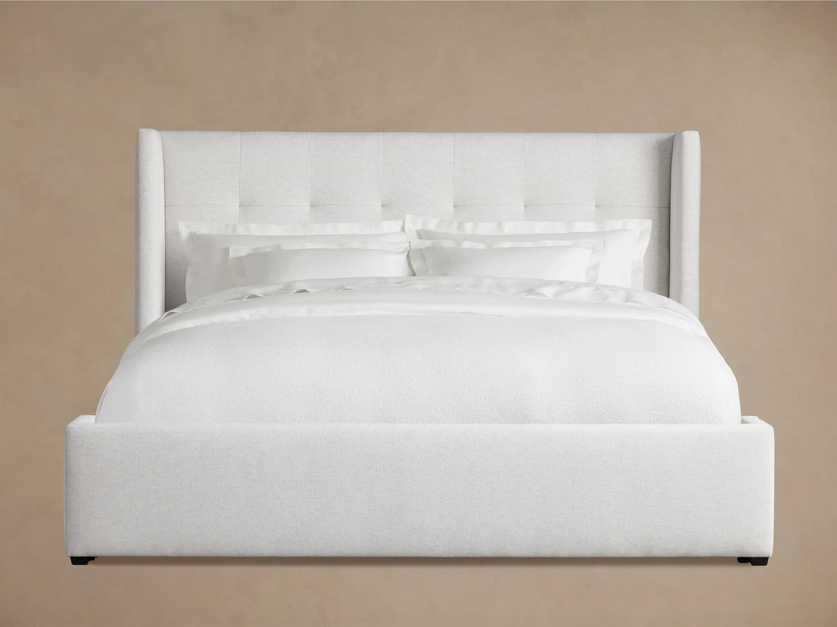 Wyller Box-Tufted Bed with low footboard. Light grey upholstered, box-tufted headboard & white bedding in an angled room.
