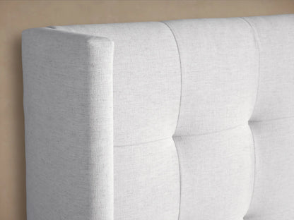 Light gray upholstered Wyller Box-Tufted Bed with winged, box-tufted headboard, low footboard, and crisp white bedding.