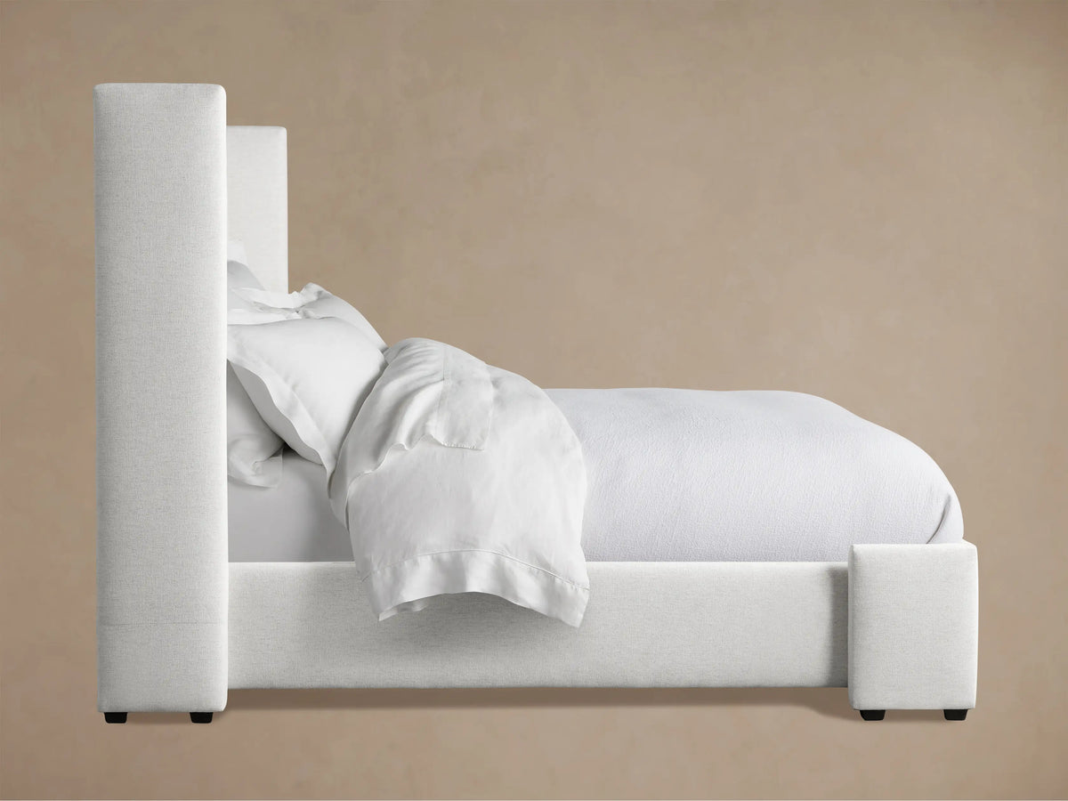 Close-up of Wyller Box-Tufted Bed headboard: light gray textured fabric, deep box-tufting, and a thick upholstered side panel.