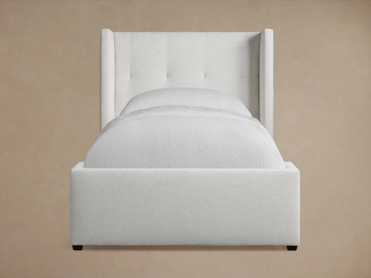 Wyller Box-Tufted Twin Bed with a light gray upholstered headboard, box tufting, and matching gray upholstered frame, on a wood floor.