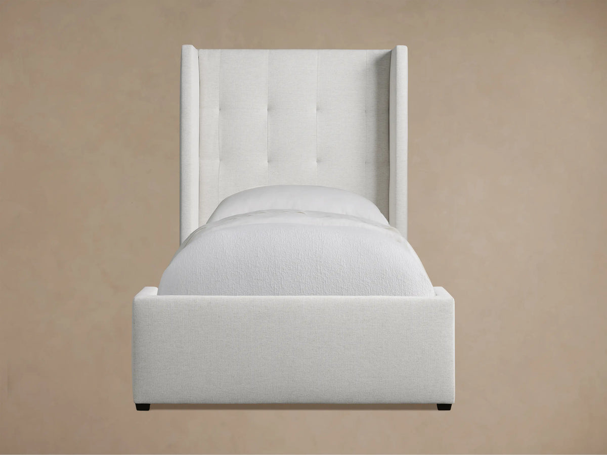 Wyller Box-Tufted Twin Bed, upholstered in light fabric, featuring a box-tufted headboard and white bedding.