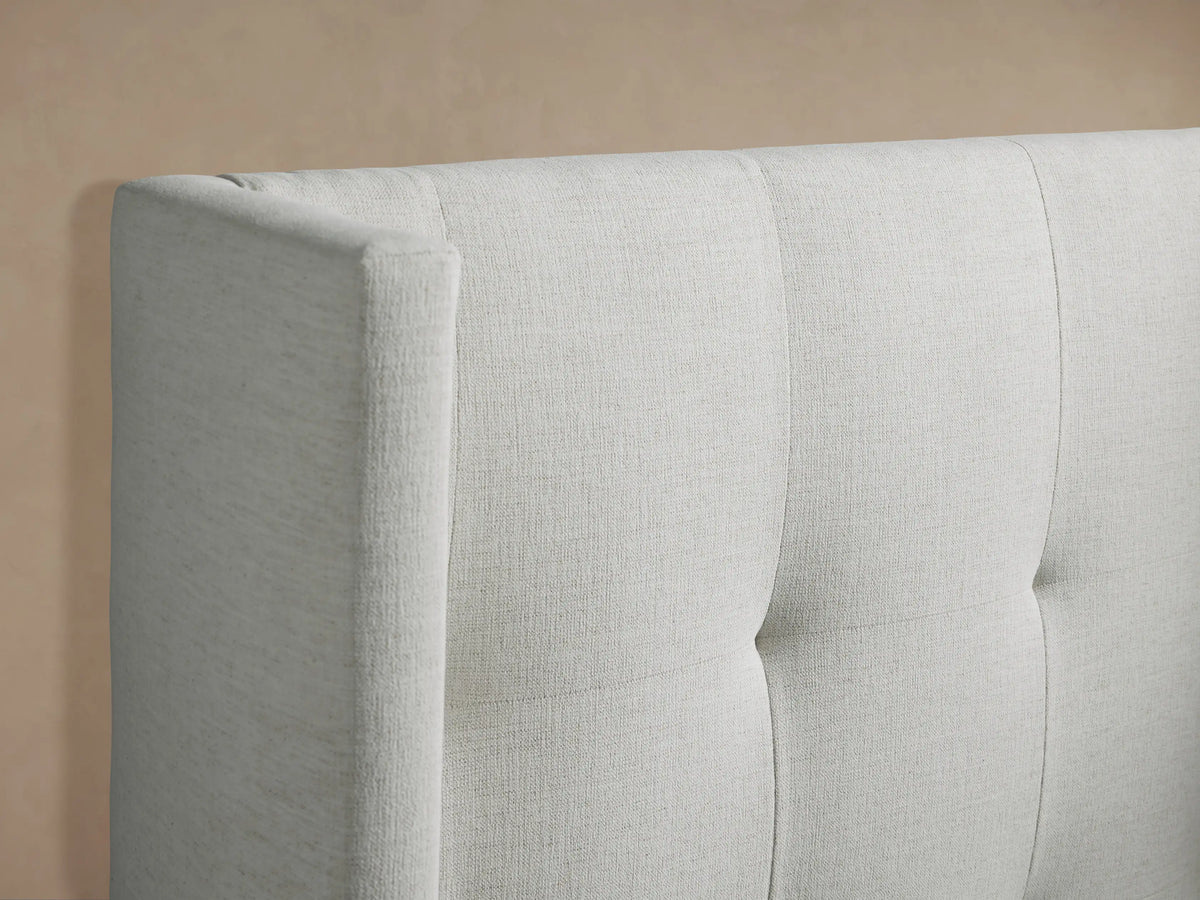 Front view of a cream upholstered Wyller Box-Tufted Twin Bed with a tall headboard, light box-tufting, and white bedding.