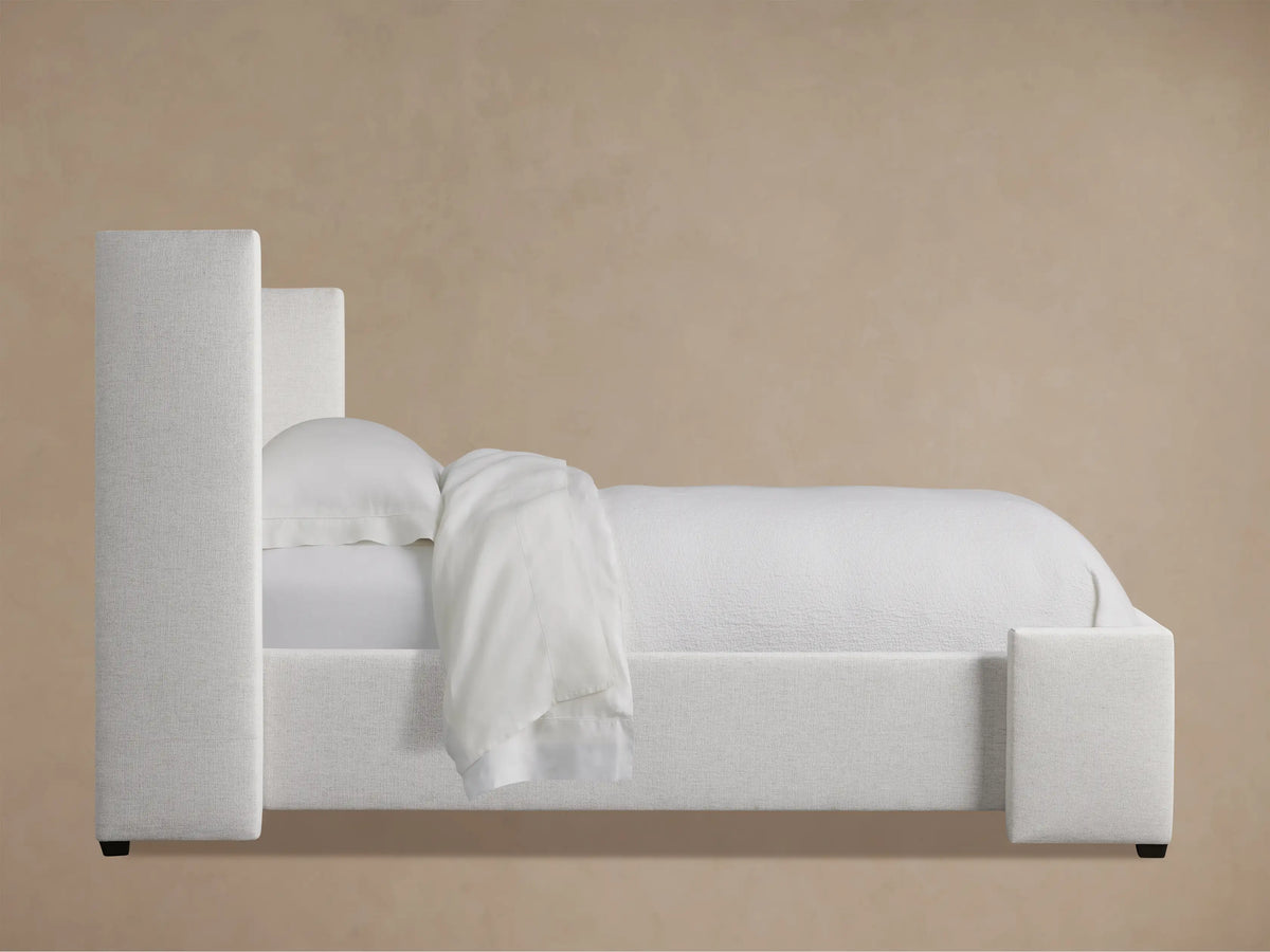 Close-up of Wyller Box-Tufted Twin Bed's light, textured fabric headboard with vertical tufting and padded side.