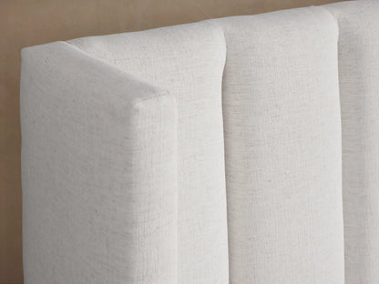 White upholstered Wyller Channel-Stitched Extended Headboard Bed with low footboard and simple white bedding.
