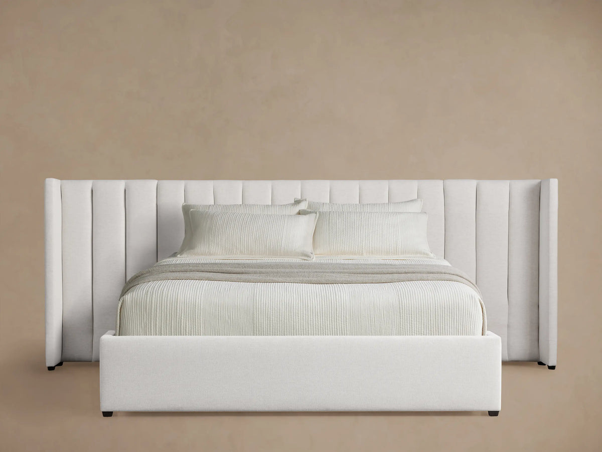 White Wyller Channel-Stitched Extended Headboard Bed with low footboard & bedding, against a light brown wall.