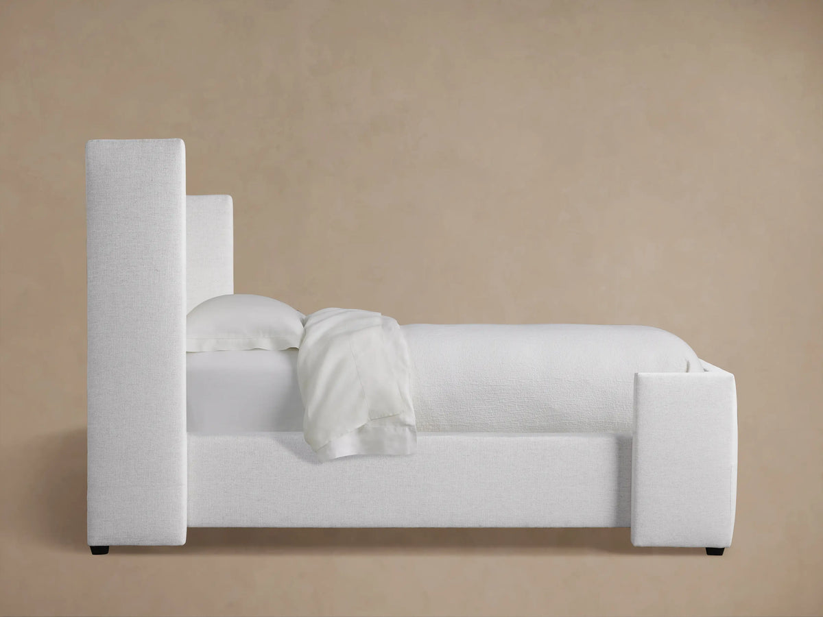 Close-up, angled view of Wyller Box-Tufted Twin Bed headboard. Light gray textured fabric, plush box tufting & buttons.