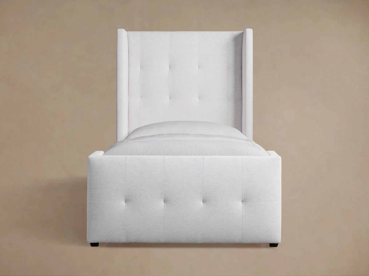 Upholstered light gray Wyller Box-Tufted Twin Bed with tall, plush headboard & footboard, white bedding, wood floor.