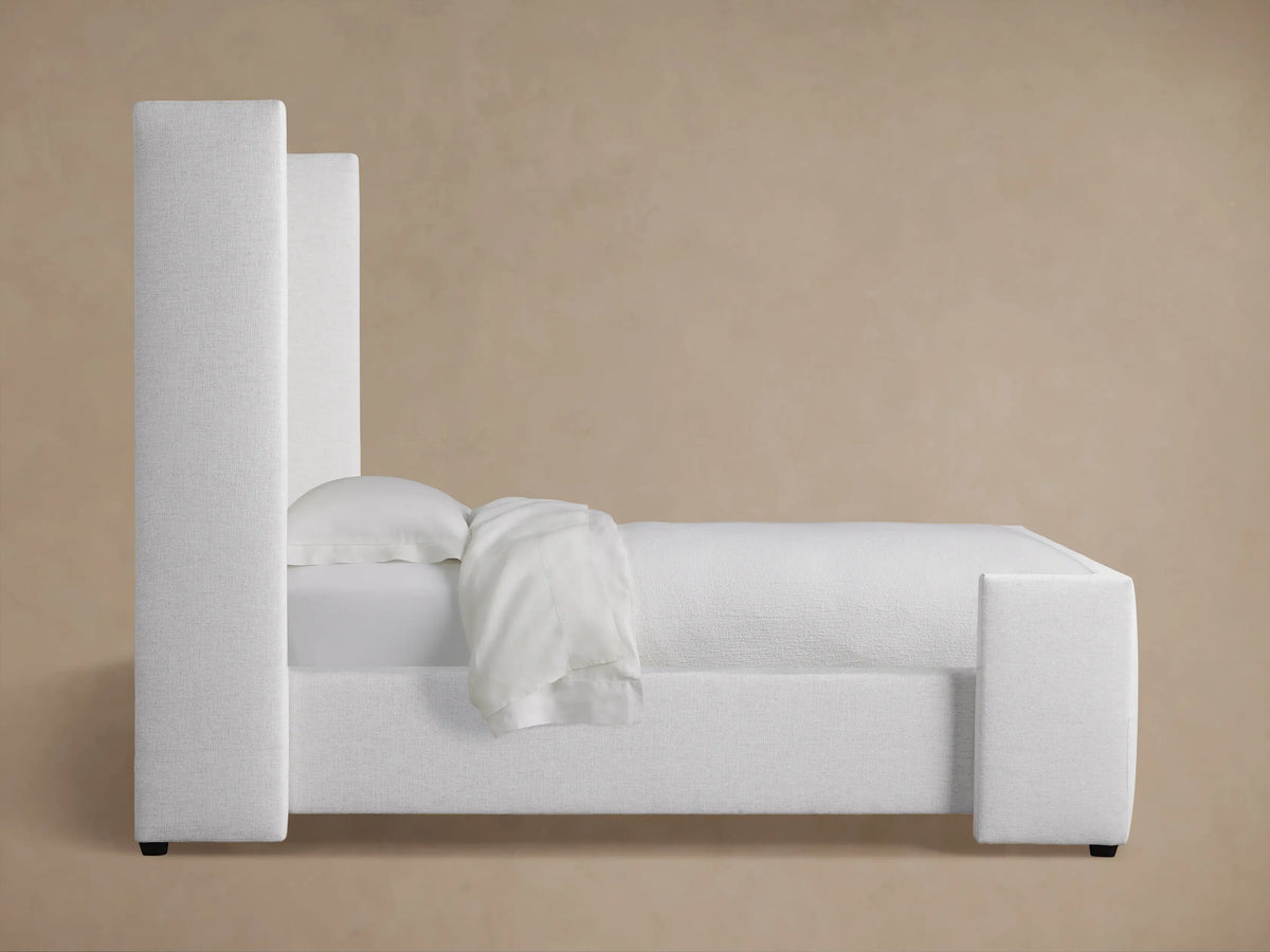 Close-up of a light gray upholstered Wyller Twin Bed headboard, showing textured fabric and box-tufted detailing.