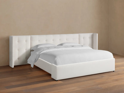 Wyller white box-tufted extended headboard bed with low footboard, in a room with tan walls and wood floor.