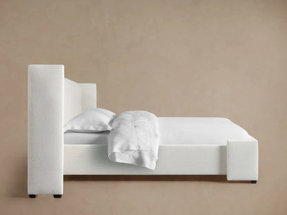 Wyller Box-Tufted Extended Headboard, angled close-up. Light off-white textured fabric with vertical tufting and deep box detail.