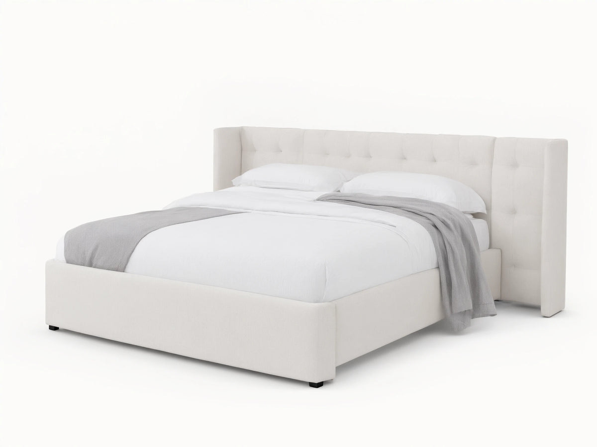 Wyller white box-tufted extended headboard bed with low footboard, in a room with tan walls and wood floor.