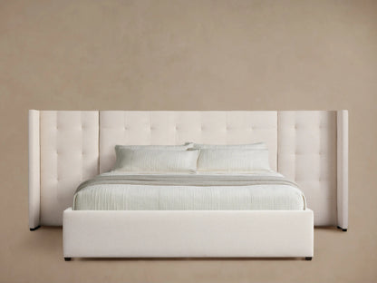 White Wyller Box-Tufted Extended Headboard Bed with low footboard and light neutral bedding on wood floor.