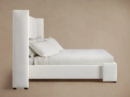 Close-up, angled view of Wyller Box-Tufted Extended Headboard in off-white textured fabric, with a side panel and a visible tuft.