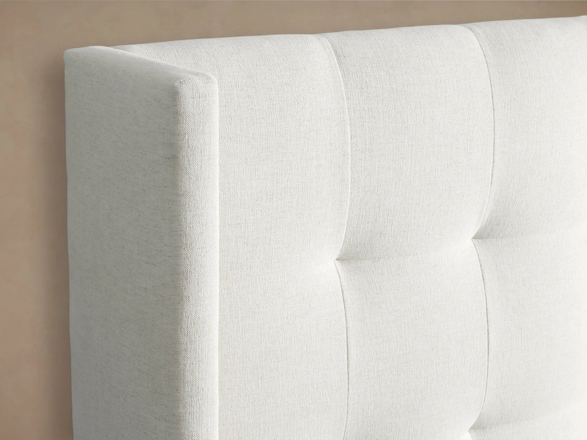 White Wyller box-tufted upholstered bed with extended headboard, low footboard, and white bedding on a beige background.
