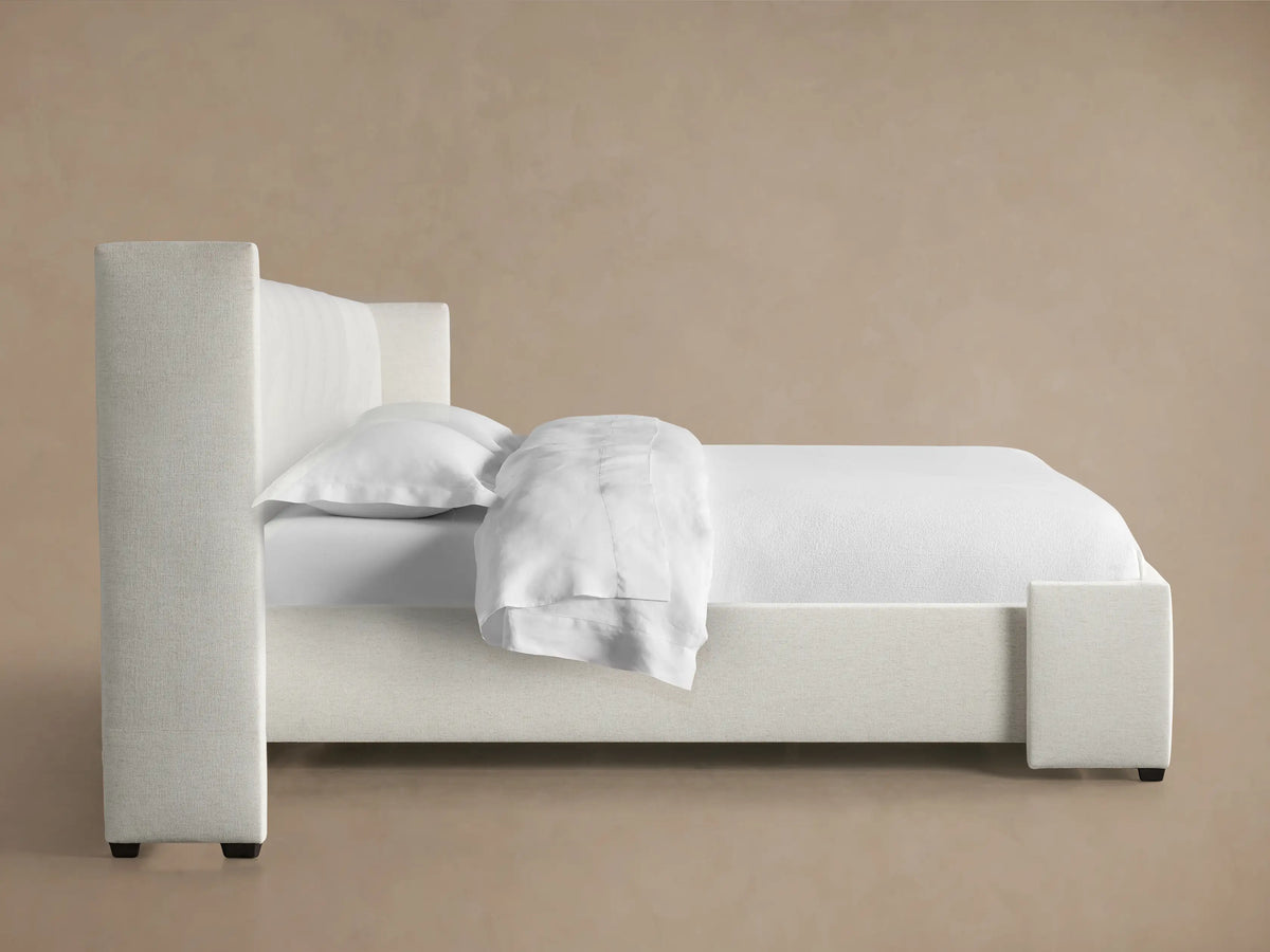 Close-up of Wyller extended headboard with box-tufting, upholstered in light beige textured fabric.