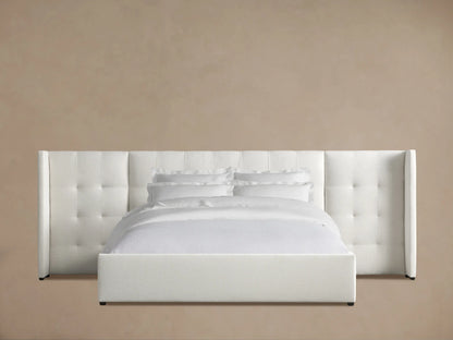 Wyller Box-Tufted Extended Headboard Bed with low footboard, upholstered in off-white fabric, with white bedding, on wood floor.