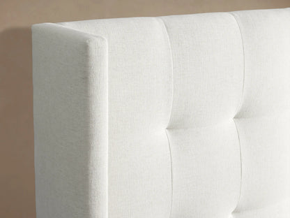 White Wyller Box-Tufted Extended Headboard Bed with crisp white bedding. Wide, box-tufted headboard & low footboard against a beige wall.