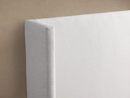 Wyller upholstered bed: extended white headboard with angled side panels, low footboard, white bedding.