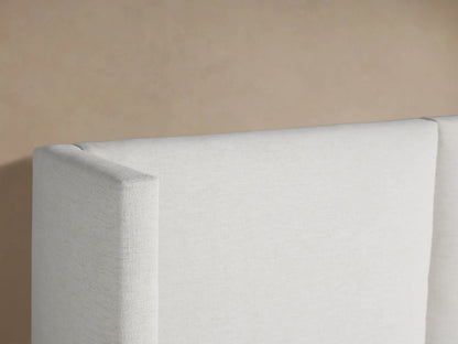 Wyller Extended Headboard Bed: white upholstered, low footboard, large three-panel headboard, white bedding against a neutral background.