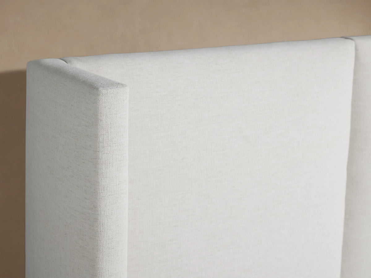 White Wyller Extended Headboard Bed with low footboard, white bedding, centered against a light brown wall.
