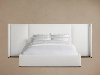 Wyller Extended Headboard Bed, white upholstered, low footboard, crisp white bedding, wooden floor, light brown wall.