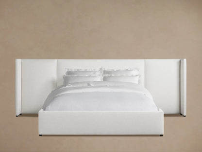White Wyller Extended Headboard Bed with low footboard against a light brown wall, featuring white bedding on a wood floor.