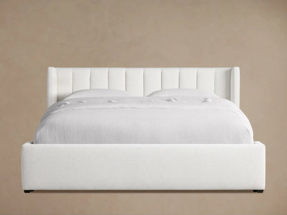 White Wyller Channel-Stitched Bed, low footboard, white bedding, angled on wood floor against beige wall.