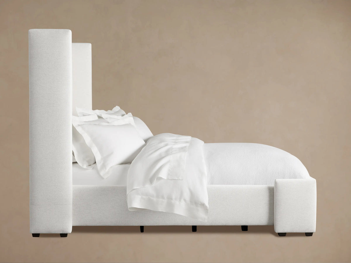 Wyller Channel-Stitched Bed's off-white fabric headboard with plush vertical channels against a warm beige wall.
