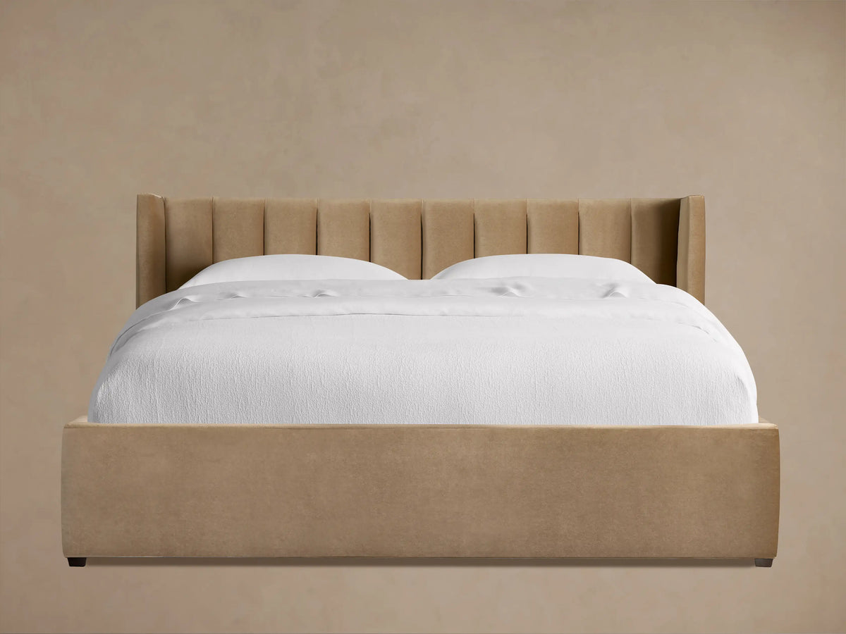Wyller bed with channel-stitched headboard and low footboard, upholstered in light brown, with white bedding.