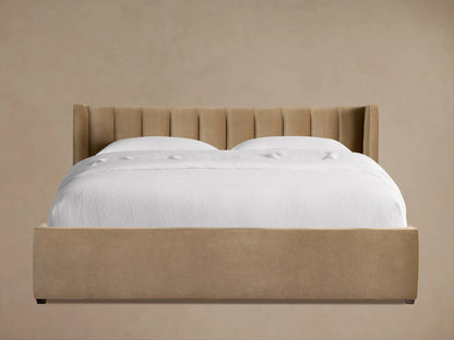 Wyller bed with channel-stitched headboard and low footboard, upholstered in light brown, with white bedding.