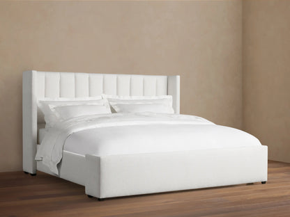 White Wyller Channel-Stitched Bed with tall, winged headboard, low footboard, & plush white bedding on wood floor.