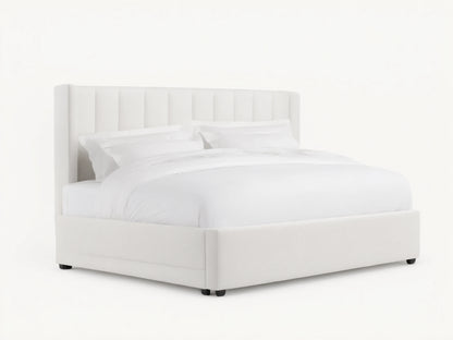 White Wyller Channel-Stitched Bed with tall, winged headboard, low footboard, & plush white bedding on wood floor.