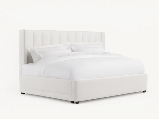 White Wyller Channel-Stitched Bed with tall, winged headboard, low footboard, & plush white bedding on wood floor.