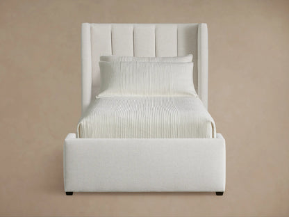 Wyller Channel-Stitched Twin Bed: Upholstered white bed with tall, channel-stitched headboard, light bedding, wood floor.
