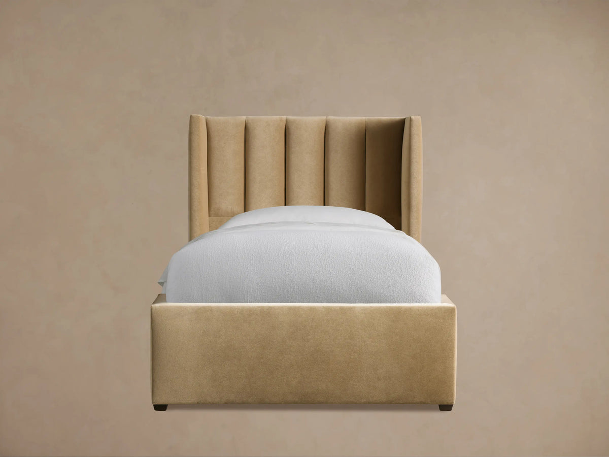Wyller Channel-Stitched Twin Bed in camel velvet, with a tall, winged channel-stitched headboard & white bedding, on wood floor.